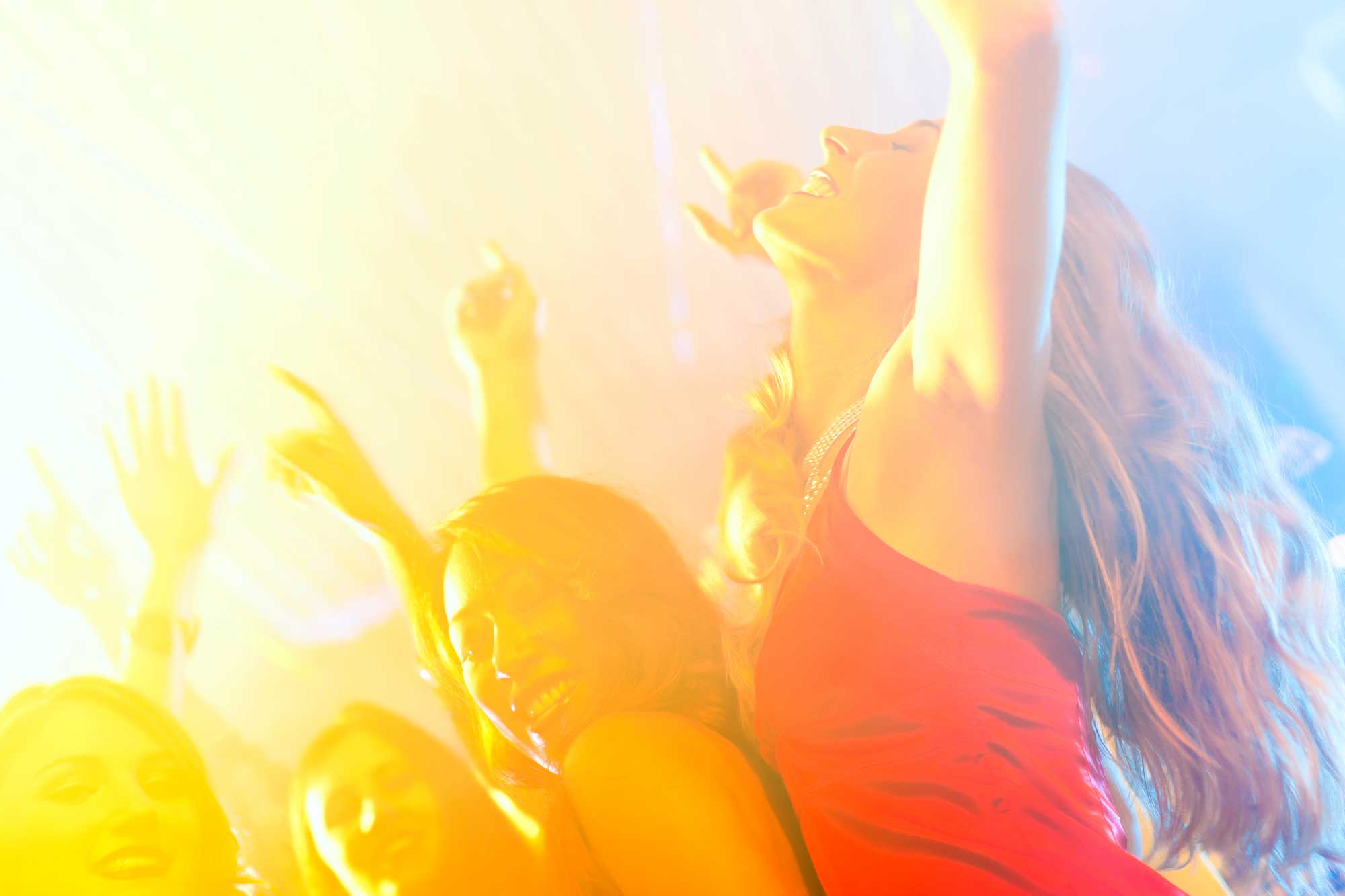 Jahrestraining I - Modul B - Menschen feiern ausgelassen im bunten Licht einer Party