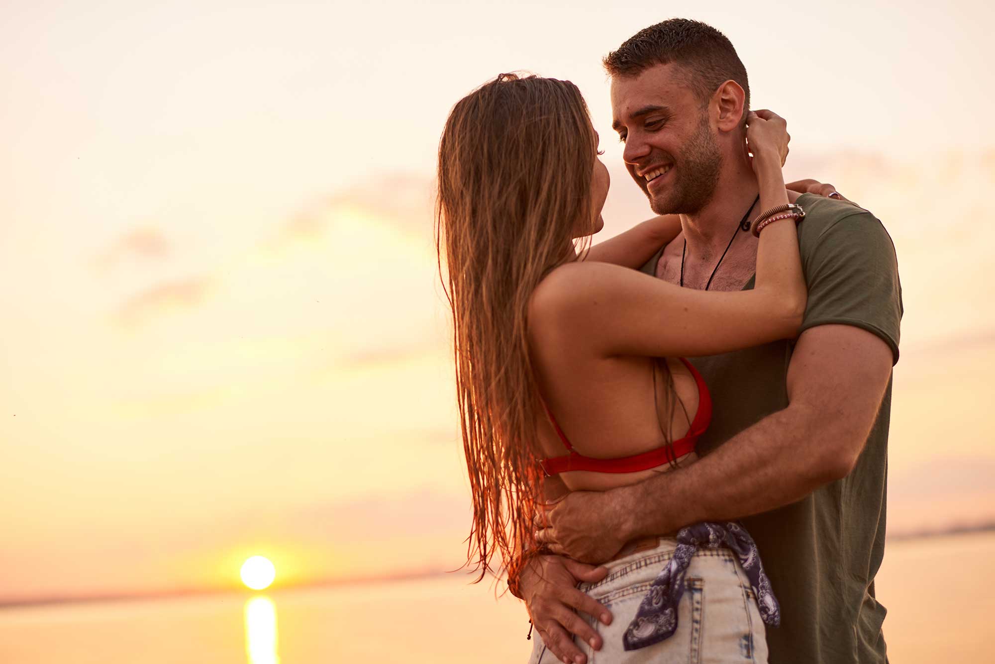 Mann und Frau umarmen sich lachend im Sonnenuntergang