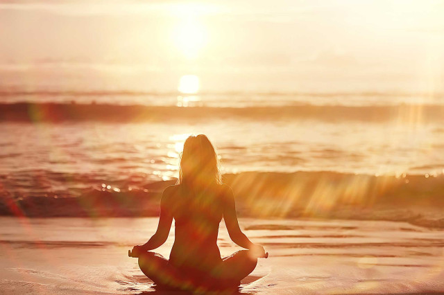 Trainings / Jahrestraining I Modul C - Essenz & Spiritualität - Frau sitzt meditierend am Strand