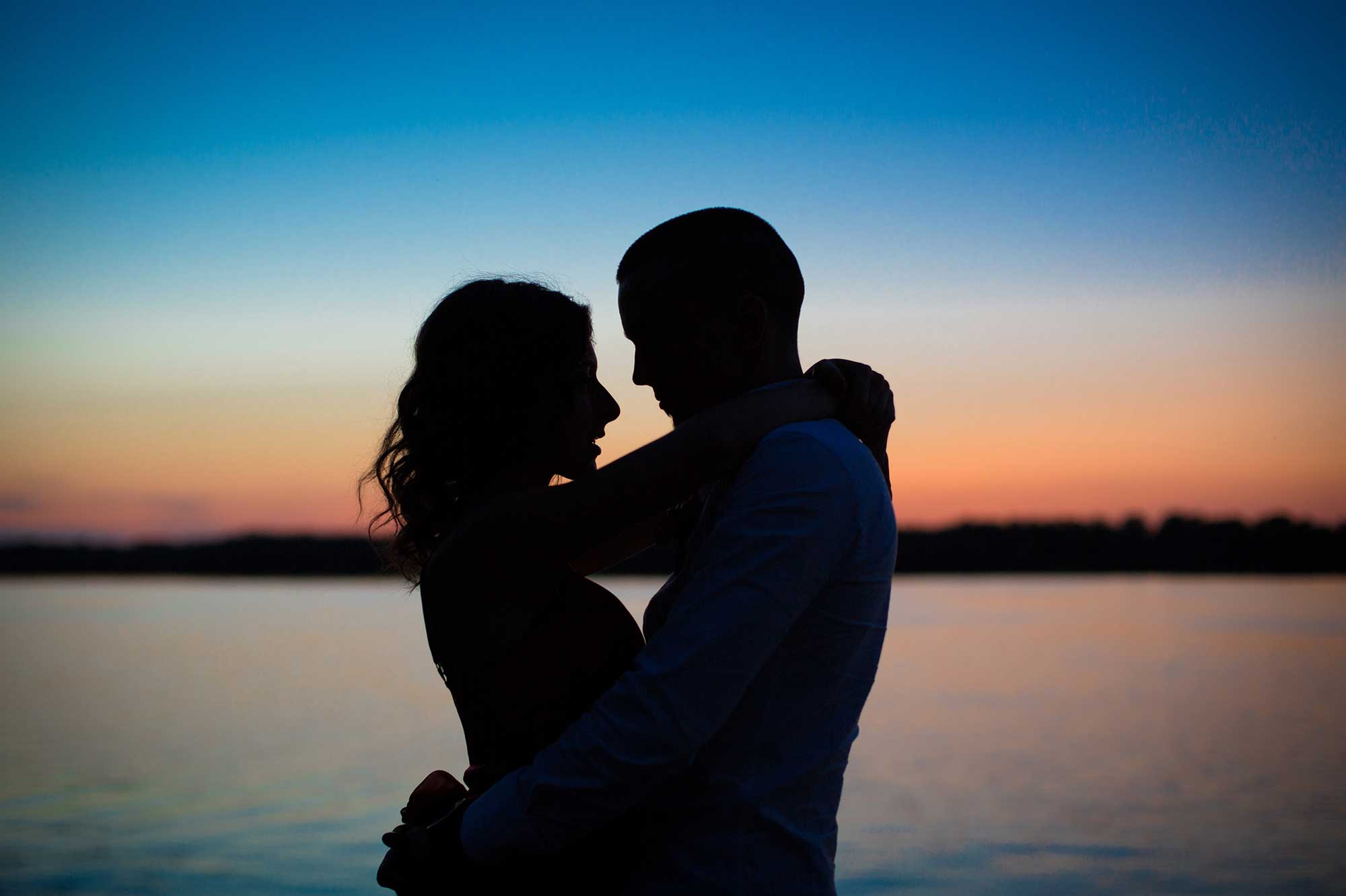 Magic Moments - Paarseminar - Paar im Sonnenuntergang am Meer. Blau-rotes Licht. Paar wirkt verliebt und innig.