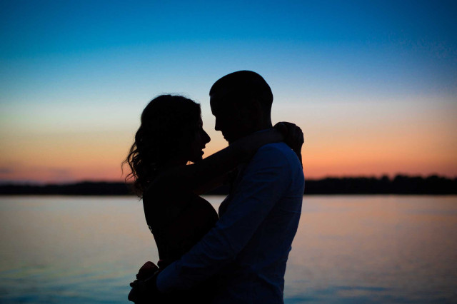 Seminare / Magic Moments - Paarseminar - Paar im Sonnenuntergang am Meer. Blau-rotes Licht. Paar wirkt verliebt und innig.