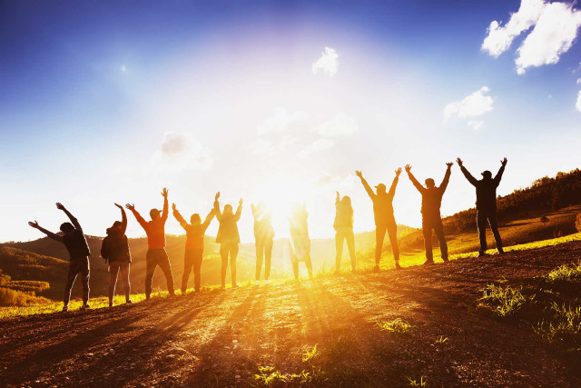 Seminare / ENERGizer - Menschen stehen auf Wiese im Sonnenschein, glücklich, verbunden